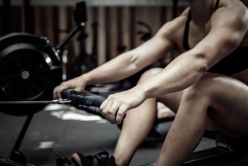 Femme sportive qui pratique des exercices sur rameur pour un entrainement complet ou ciblé.
