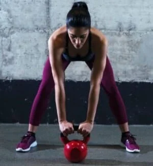 Une femme qui fait des exercices avec un kettlebell.