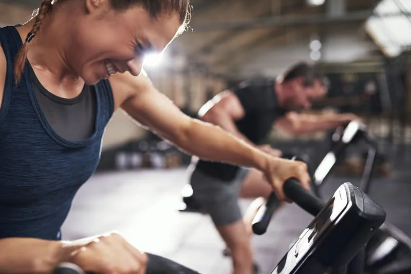Femme sportive en séance d'entrainement intense HIIT sur appareil cardio.