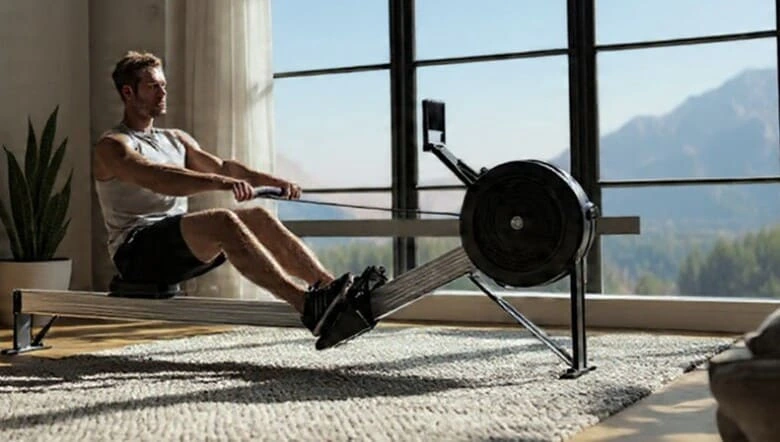 Homme sportif qui s'entraine dans son salon, sur son rameur indoor bien choisi.