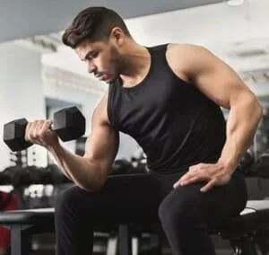 un homme en entrainement de musculation avec un haltère.