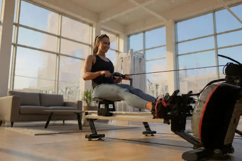 Femme sportive qui s'entraine sur un rameur d'appartement et qui profite de tous les bienfaits de ce sport complet.