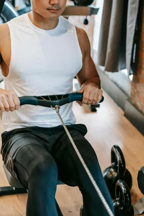 Homme sportif pratiquant le rameur d'appartement avec une pratique correcte et une bonne posture.