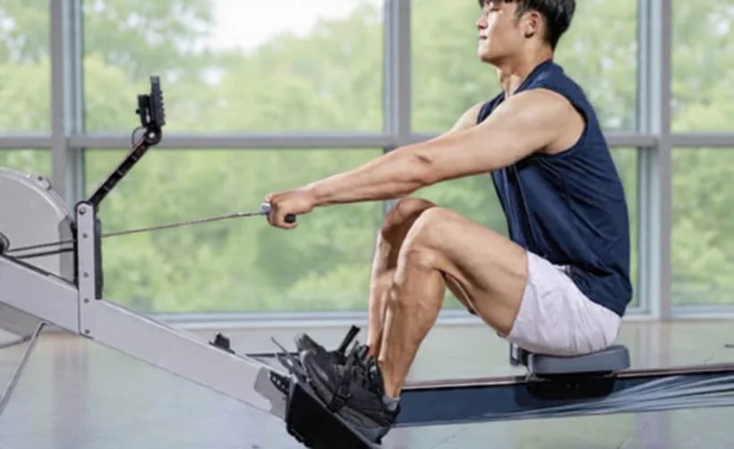 Homme sportif en entrainement de cardio-training ou renforcement musculaire sur rameur.