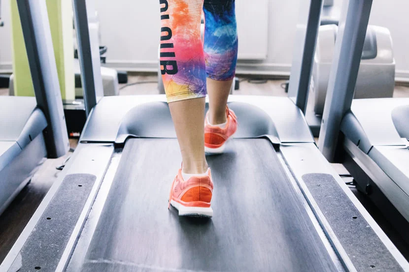 Femme sportive qui applique les conseils pour bien s'entrainer sur une tapis de course.