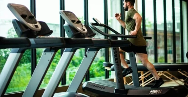 Salle contenant plusieurs modèles de tapis de course et un homme qui court sur un des modèles.