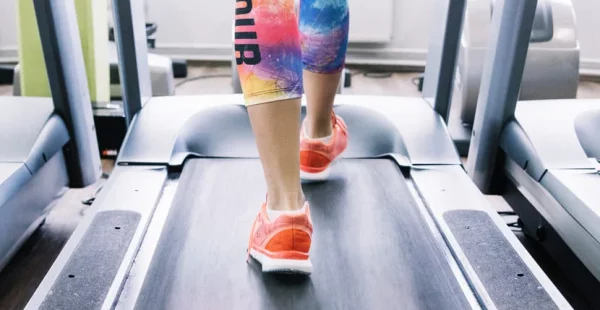 Femme sportive qui applique les conseils pour bien s'entrainer sur une tapis de course.